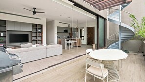 A modern living space with a sofa, TV, and dining area. - Paraíso Residence: Luxury in the Heart of the Marina (Cabo San Lucas)