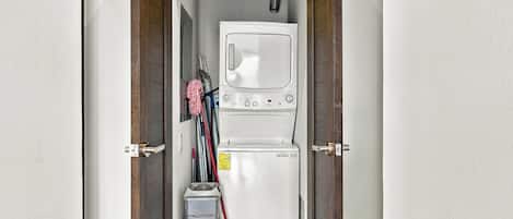 A laundry room with a washing machine and dryer, a mop, and cleaning supplies.