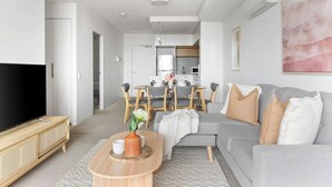 Un salon moderne avec un canapé gris, une table basse en bois et un téléviseur à écran plat.