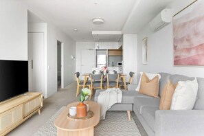 A modern living room with a grey sofa, wooden coffee table, and a flat-screen TV. - Bright Yarra Side 2BR, Modern Comfort & City Vibes (Abbotsford)