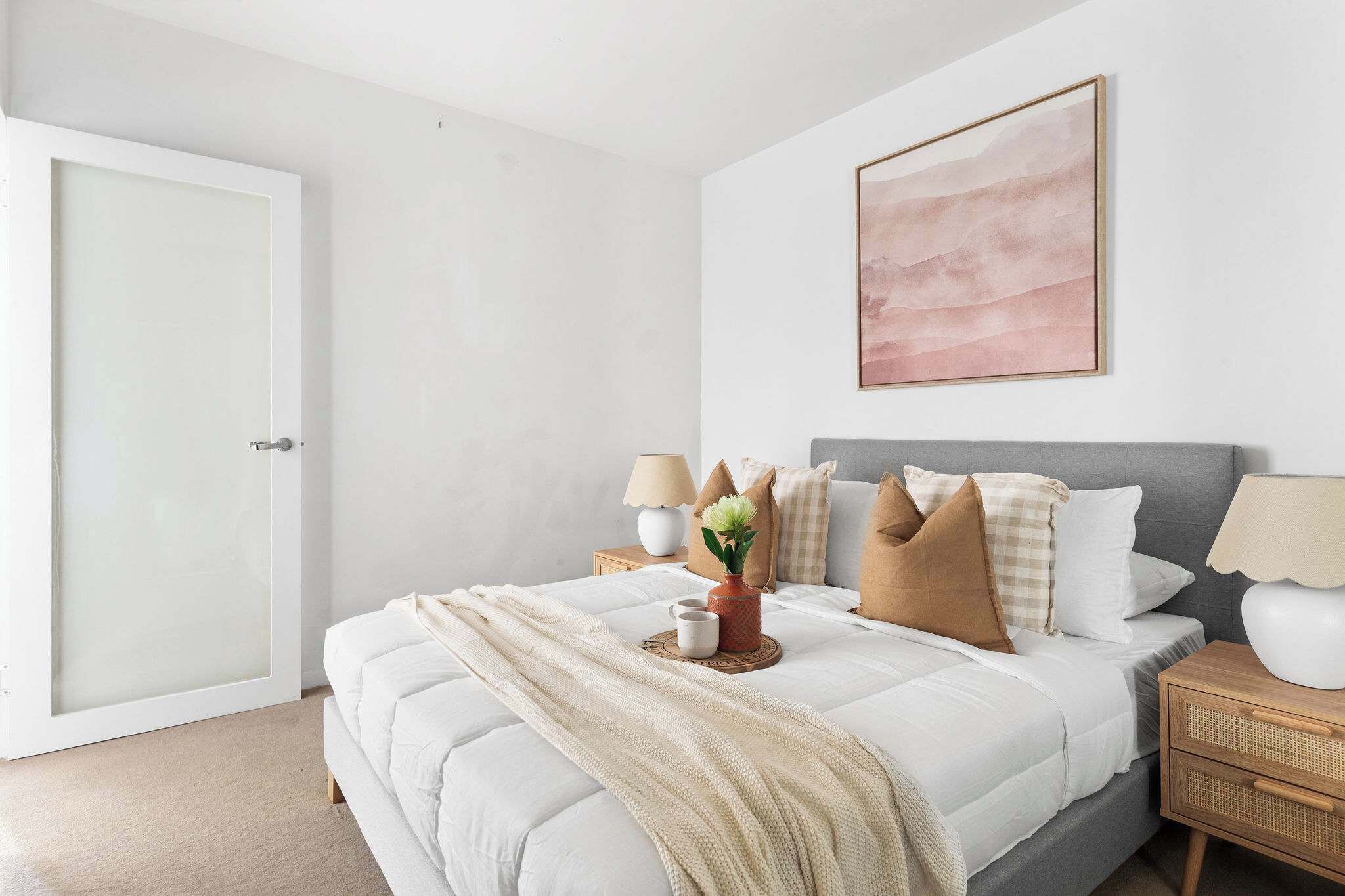 A bedroom with a bed, bedside tables, a lamp, and a painting on the wall.