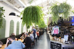 A restaurant with indoor seating, a menu board, and hanging plants. - Bright Yarra Side 2BR, Modern Comfort & City Vibes (Abbotsford)