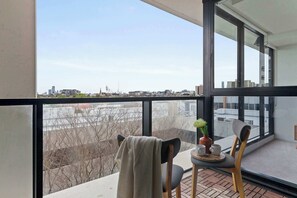 A balcony with a table, chairs, and a potted plant. - Bright Yarra Side 2BR, Modern Comfort & City Vibes (Abbotsford)