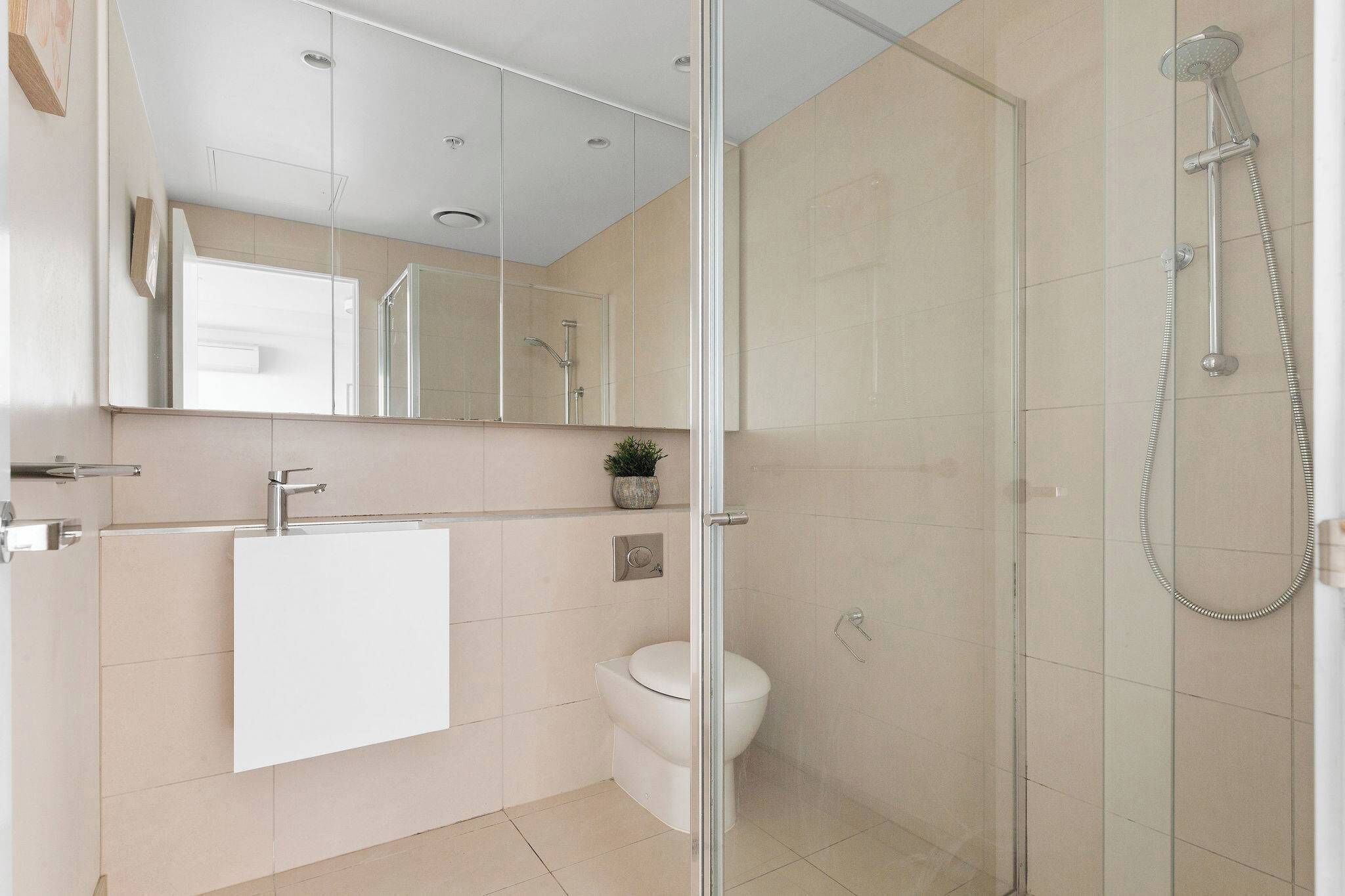 A modern bathroom with a glass-enclosed shower, a white sink, and a toilet.