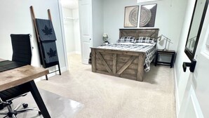 Un dormitorio con cama, escritorio y silla. Hay un armario y una puerta que da a otra habitación.