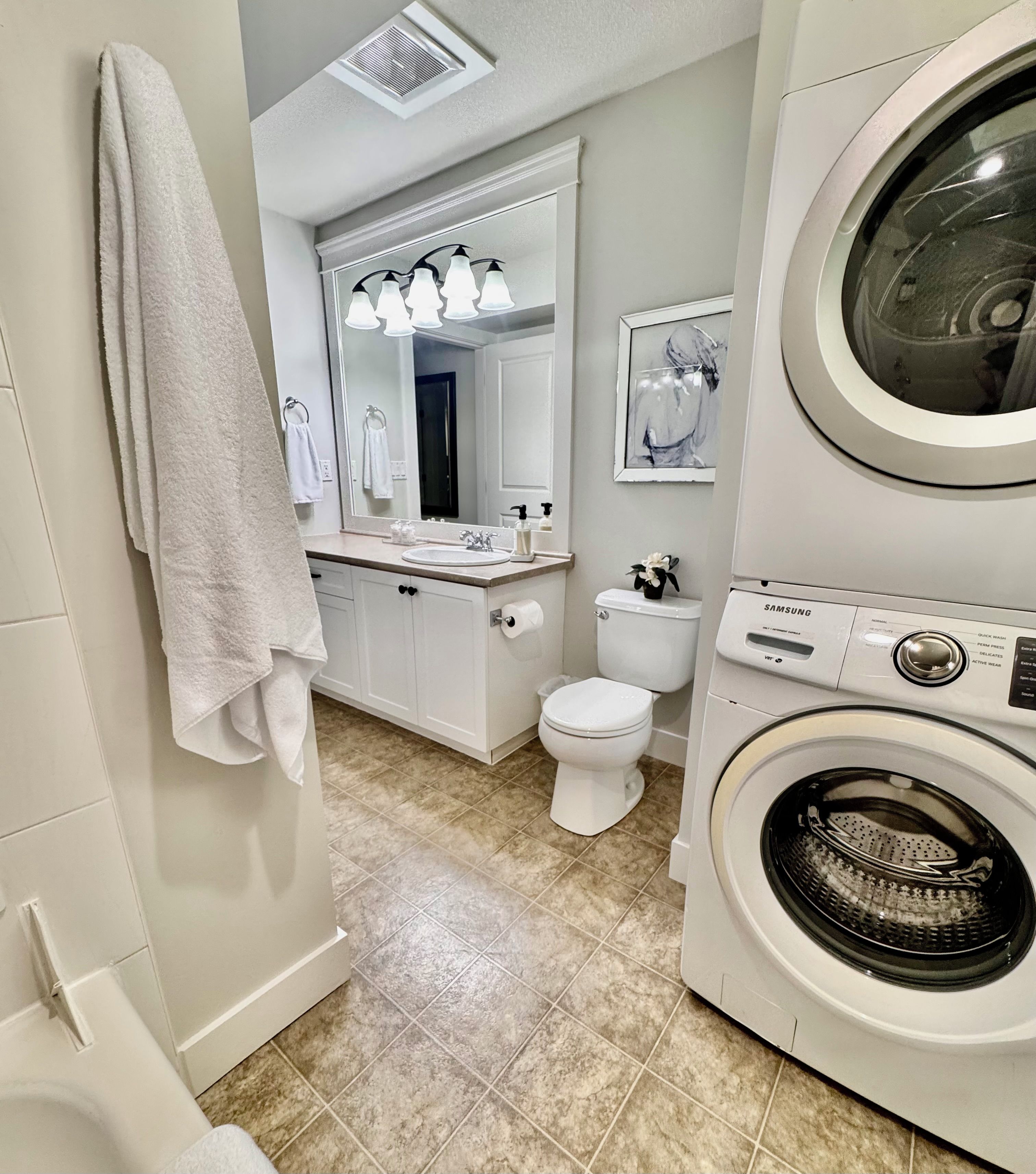 A bathroom with a washing machine, a toilet, a sink, and a mirror.