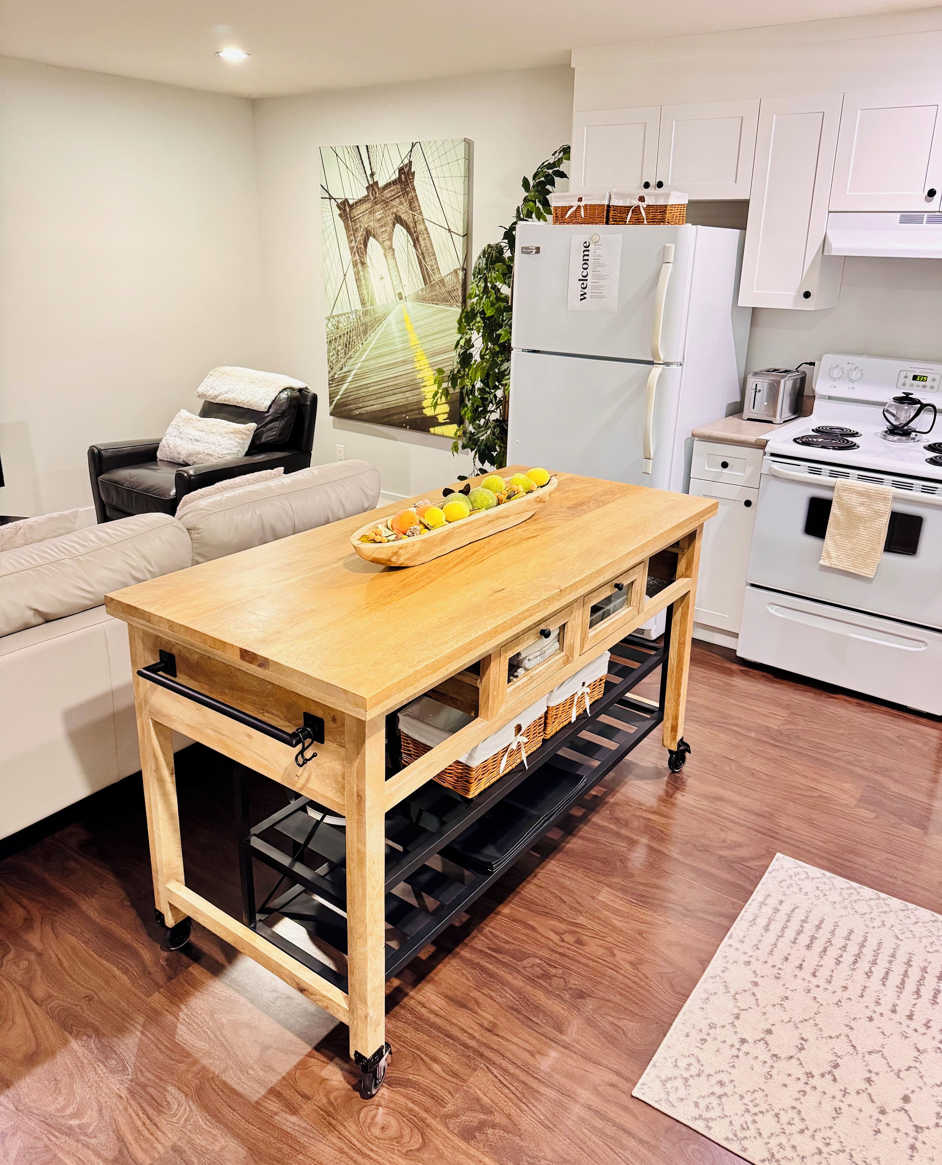 A modern kitchen with a wooden table, white cabinets, and a refrigerator.
