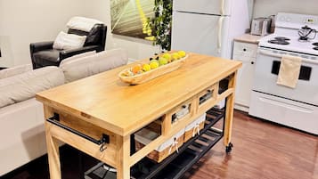 A modern kitchen with a wooden table, white cabinets, and a refrigerator.