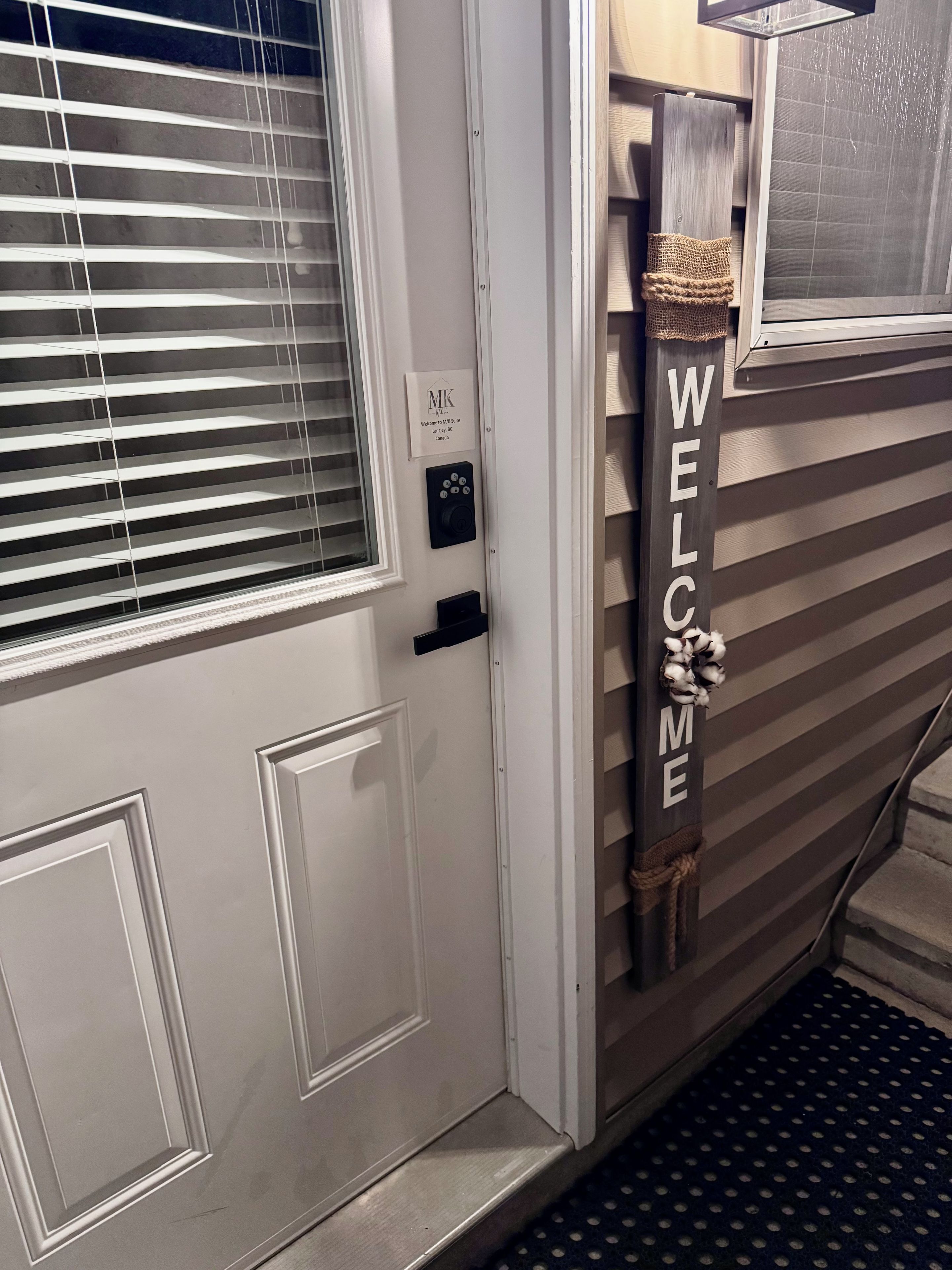 A door with a 'WELCOME' sign, a keypad lock, and a window with blinds.