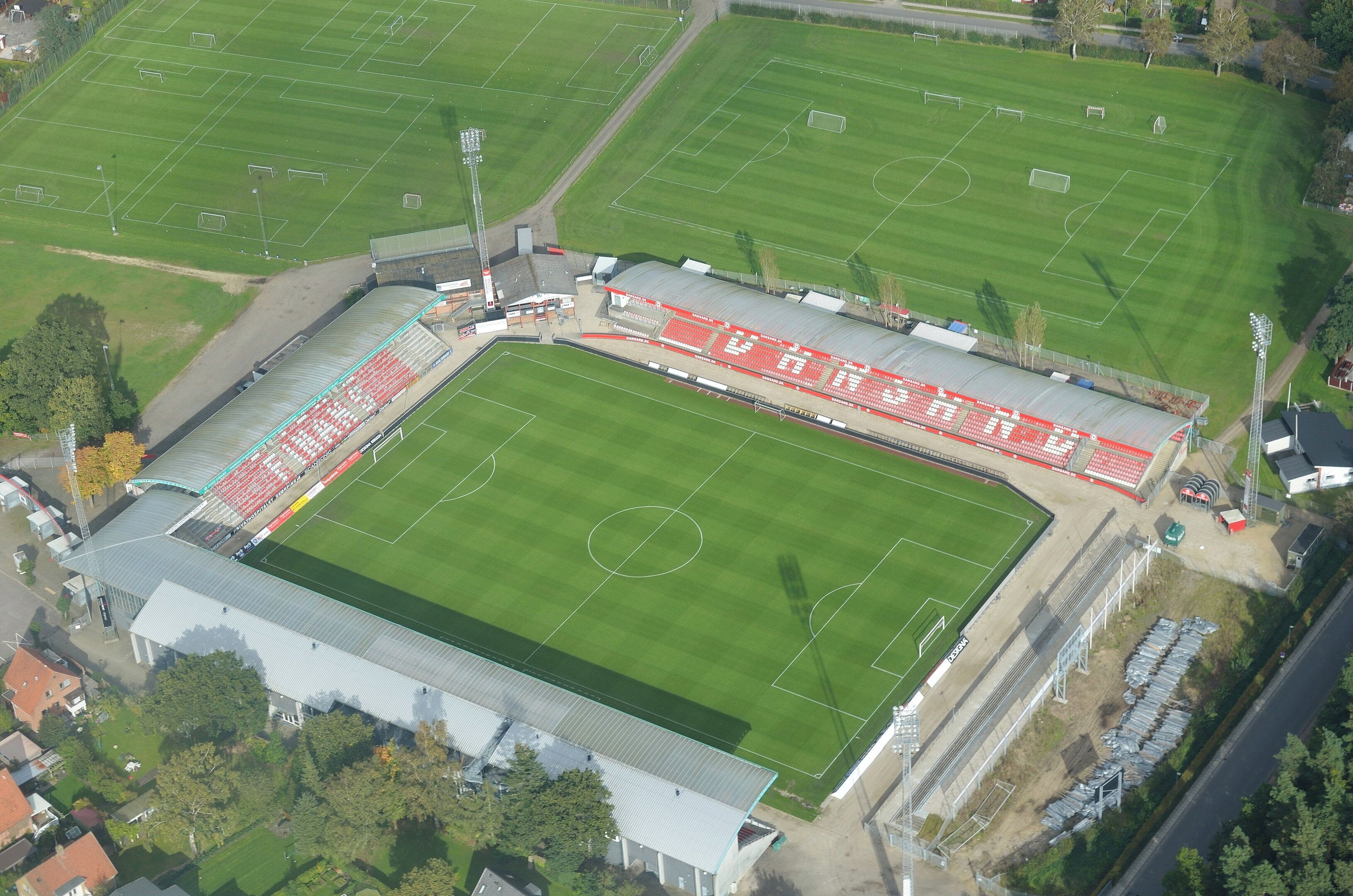 Et stort stadion med flere fodboldbaner og tilskuerpladser.