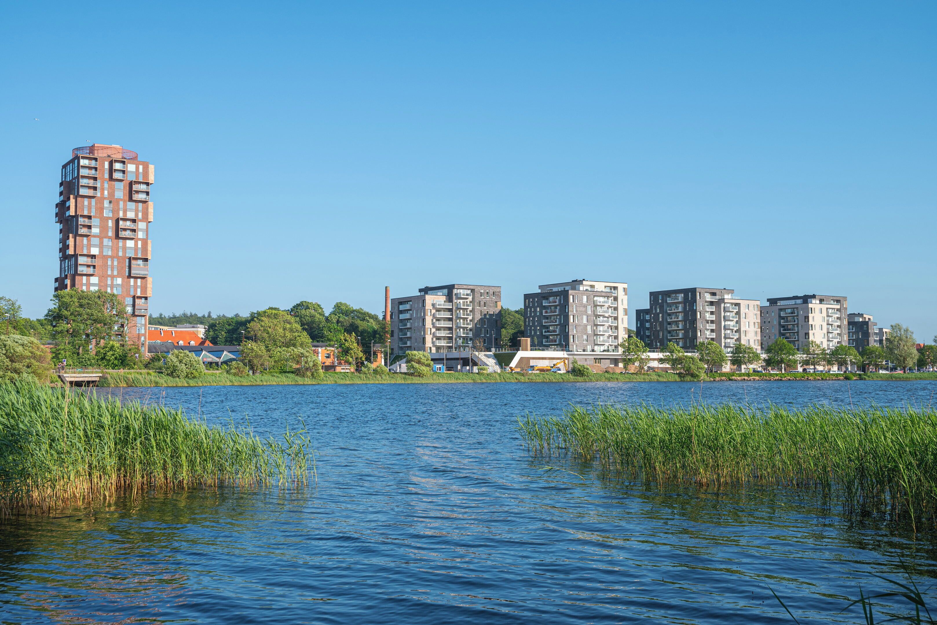 Uitzicht op het water met moderne gebouwen en een steiger.