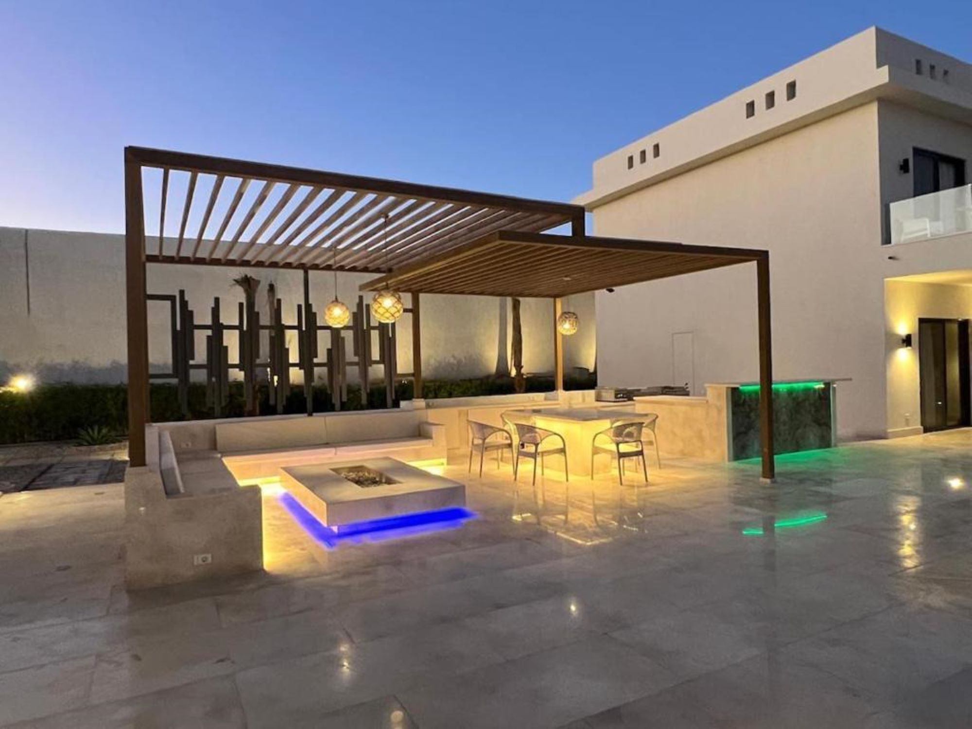 Een terras buiten met een pergola, zitplaatsen en een bar.