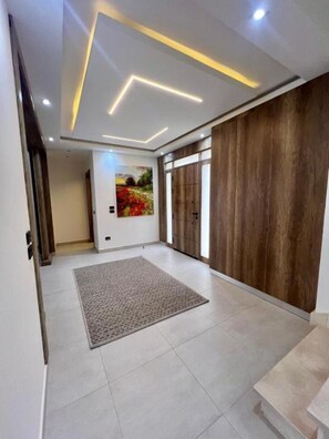 Un interior moderno con un diseño geométrico en el techo, un tapete grande y un revestimiento de pared de madera.
