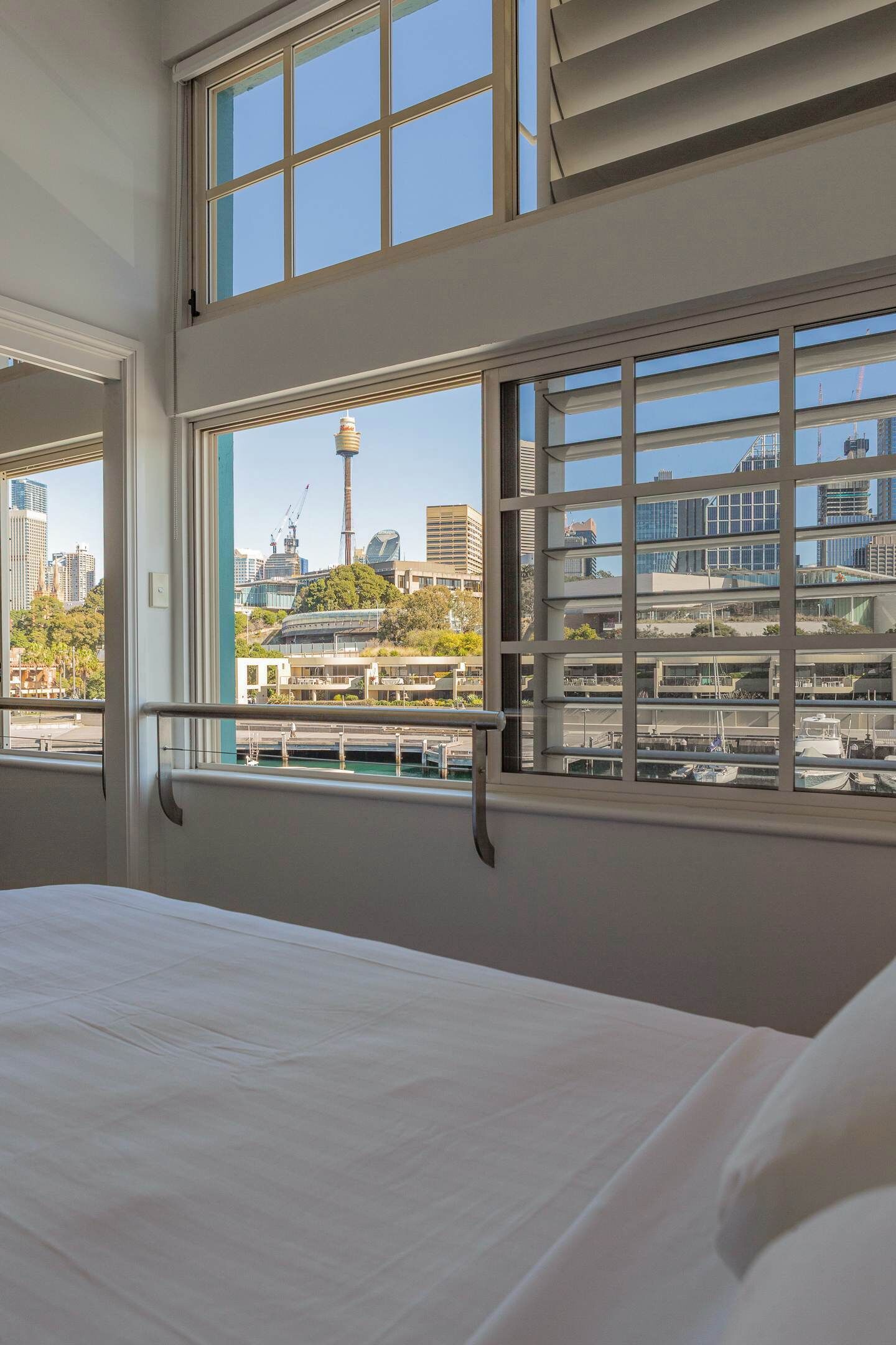 Une chambre d’hôtel avec un grand lit, une fenêtre donnant sur le paysage urbain et une balustrade de balcon.