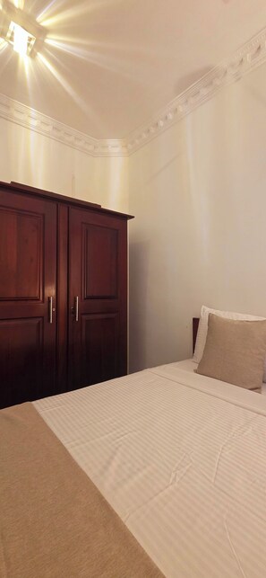 Ein Schlafzimmer mit Bett, Kleiderschrank und Deckenleuchte.
