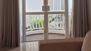 A room with a sofa, a ceiling light fixture, and a view through a glass door to an outdoor area with plants. - Luxury 3BR Apartment Nugegoda bordering Colombo 5 (Nugegoda)