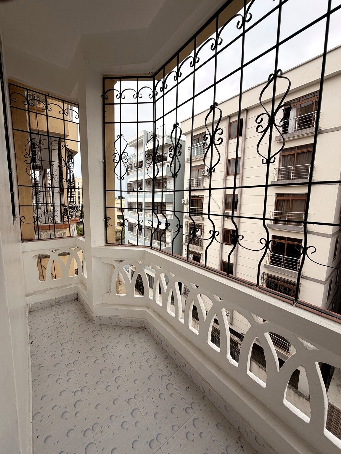 A balcony with a white railing and a view of adjacent buildings.