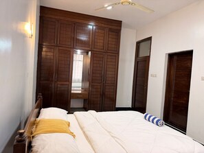 Un dormitorio con una cama, un armario de madera y un ventilador de techo.