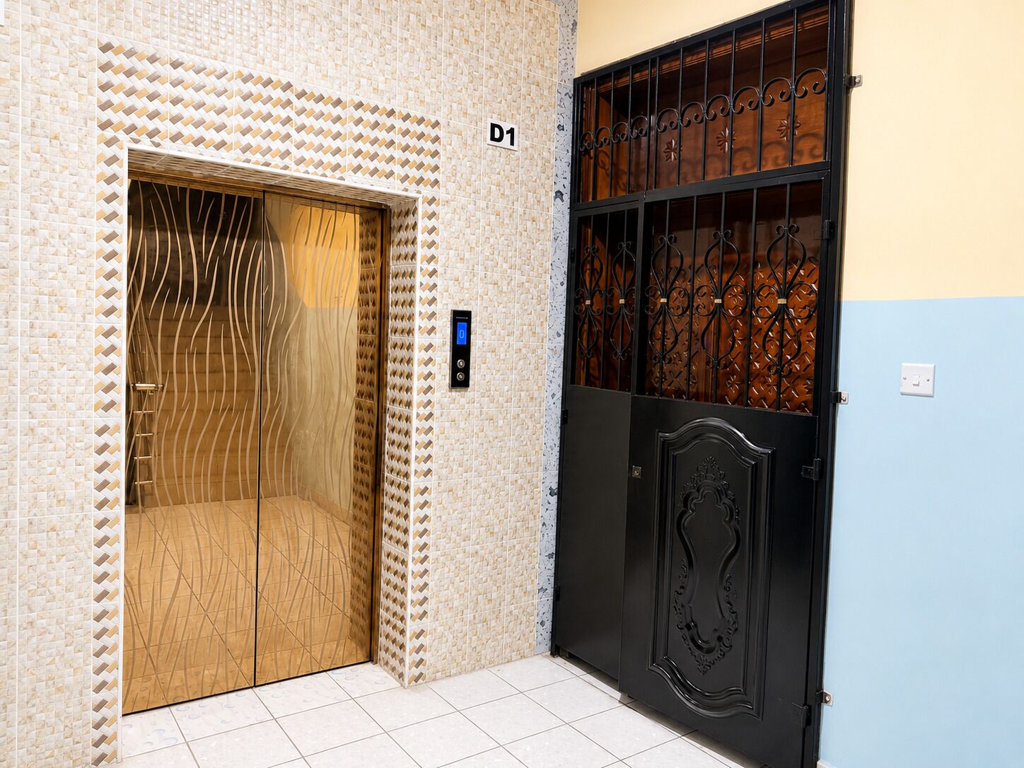 An elevator with a digital display, a wooden door, and a black gate with decorative metalwork.