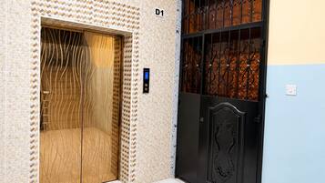 An elevator with a digital display, a wooden door, and a black gate with decorative metalwork.