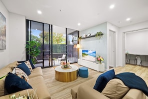 A modern living room with a sofa, coffee table, and a TV.
