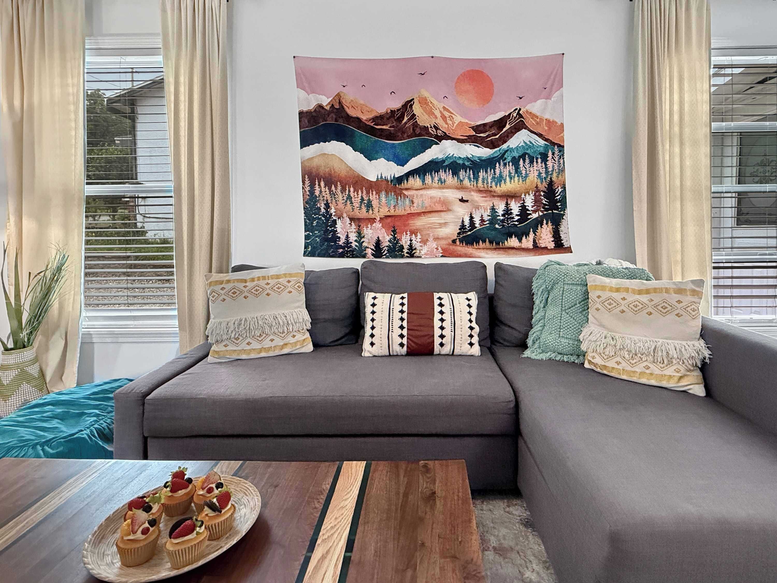 A living room with a gray sofa, decorative pillows, a wooden coffee table, and a wall tapestry.