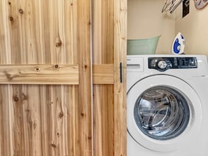 Une porte en bois avec une poignée et un lave-linge blanc doté d’un panneau de commande.