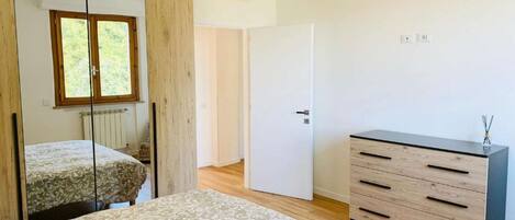 A bedroom with a bed, a dresser, a mirror, and a door.