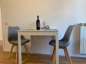 A dining table with two chairs, a wine bottle, and a glass. - A smart and efficient apartment, perfect for couples or business stays near Siena. (Sovicille)