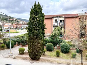A residential area with a tall coniferous tree, a brick building with balconies, and a clear sky. - A comfortable and practical apartment, ideal for work stays and exploring Siena. (sovicille)