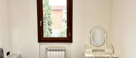Un dormitorio con cama, un aparador blanco con espejo y un radiador.