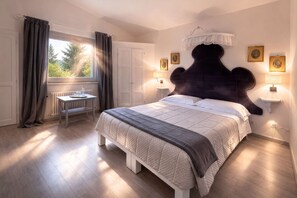 Ein Schlafzimmer mit einem großen Bett, Nachttischlampen, einem Fenster mit Vorhängen und einer Heizung.
