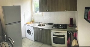 Eine kompakte Küche mit Waschmaschine, Kühlschrank, Spüle und Backofen.