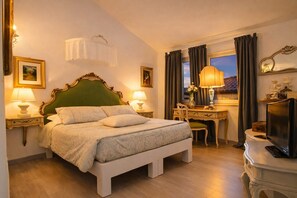 Ein Hotelzimmer mit einem Bett, Nachttischlampen, einem Schreibtisch mit Stuhl, einem Fernseher und einem Fenster mit Vorhängen.