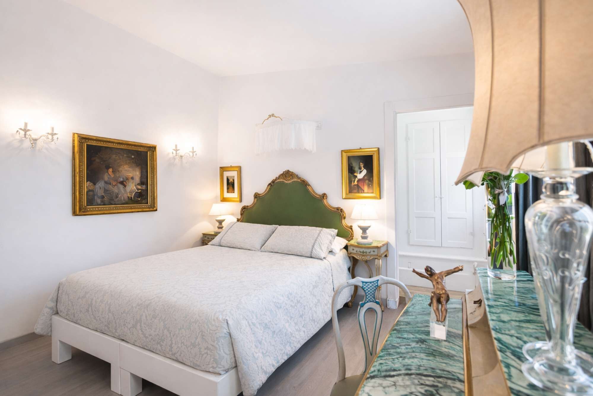 A bedroom with a bed, bedside tables, a chair, and a vase.