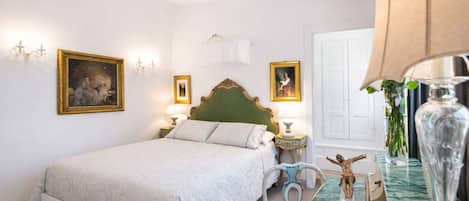 A bedroom with a bed, bedside tables, a chair, and a vase.