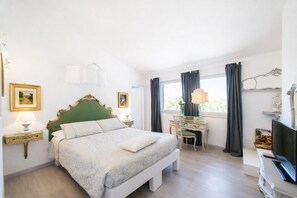 Ein Schlafzimmer mit einem Bett, einem Schreibtisch, einem Stuhl, einer Lampe und einem Fernseher.
