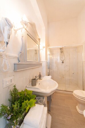 Ein Badezimmer mit Waschbecken, Spiegel, Föhn und Duschkabine.