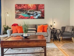 Un salon avec un canapé, une table basse et un tableau représentant une cascade.