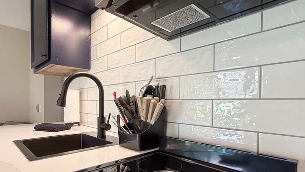A modern kitchen with a black countertop, a sink, and a range hood. - No stairs, clean peaceful secluded, close to strip (Branson)