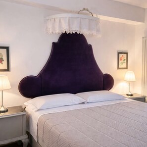 Ein Bett mit einem violetten Kopfteil, weißen Kissen und einer weißen Bettdecke.