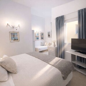 Ein modernes Schlafzimmer mit Bett, Fernseher, Kommode und Spiegel.