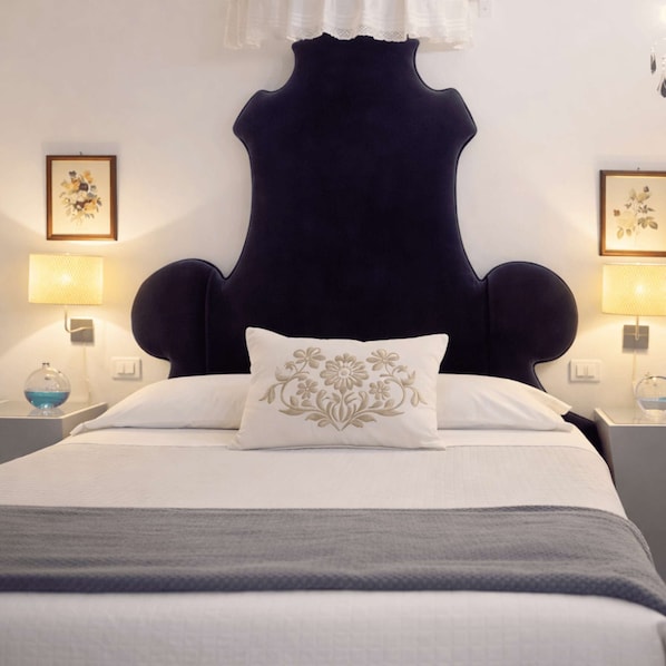 Ein Bett mit dunklem Kopfteil, weißer Bettwäsche und einem Zierkissen.