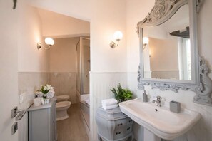 Ein Badezimmer mit einem weißen Waschbecken, einem großen Spiegel und einer Duschkabine.