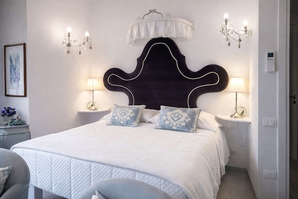 Ein Schlafzimmer mit einem großen Bett, zwei Nachttischlampen, einem dekorativen Kopfteil und einer Wandleuchte.