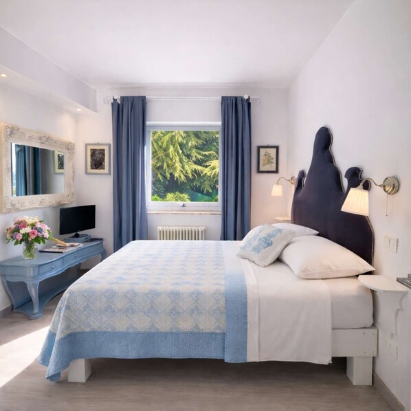 Ein Schlafzimmer mit einem Bett, einem Schreibtisch, einem Stuhl, einem Spiegel, einem Fenster mit Vorhängen und einer Heizung.