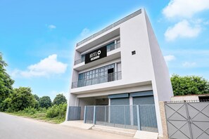 Un hotel moderno con fachada plana, un llamativo letrero 'HOTEL' y una entrada con portones.