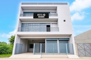 A modern hotel building with a sign that reads 'HOTEL OYO-Serviced.'
