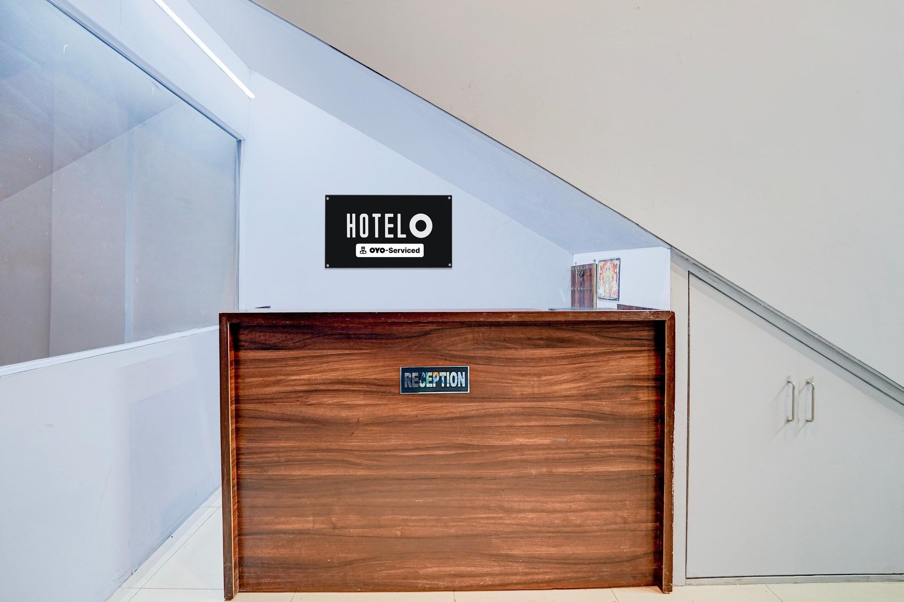 A hotel reception area with a wooden reception desk and a sign indicating it is serviced by OYO.