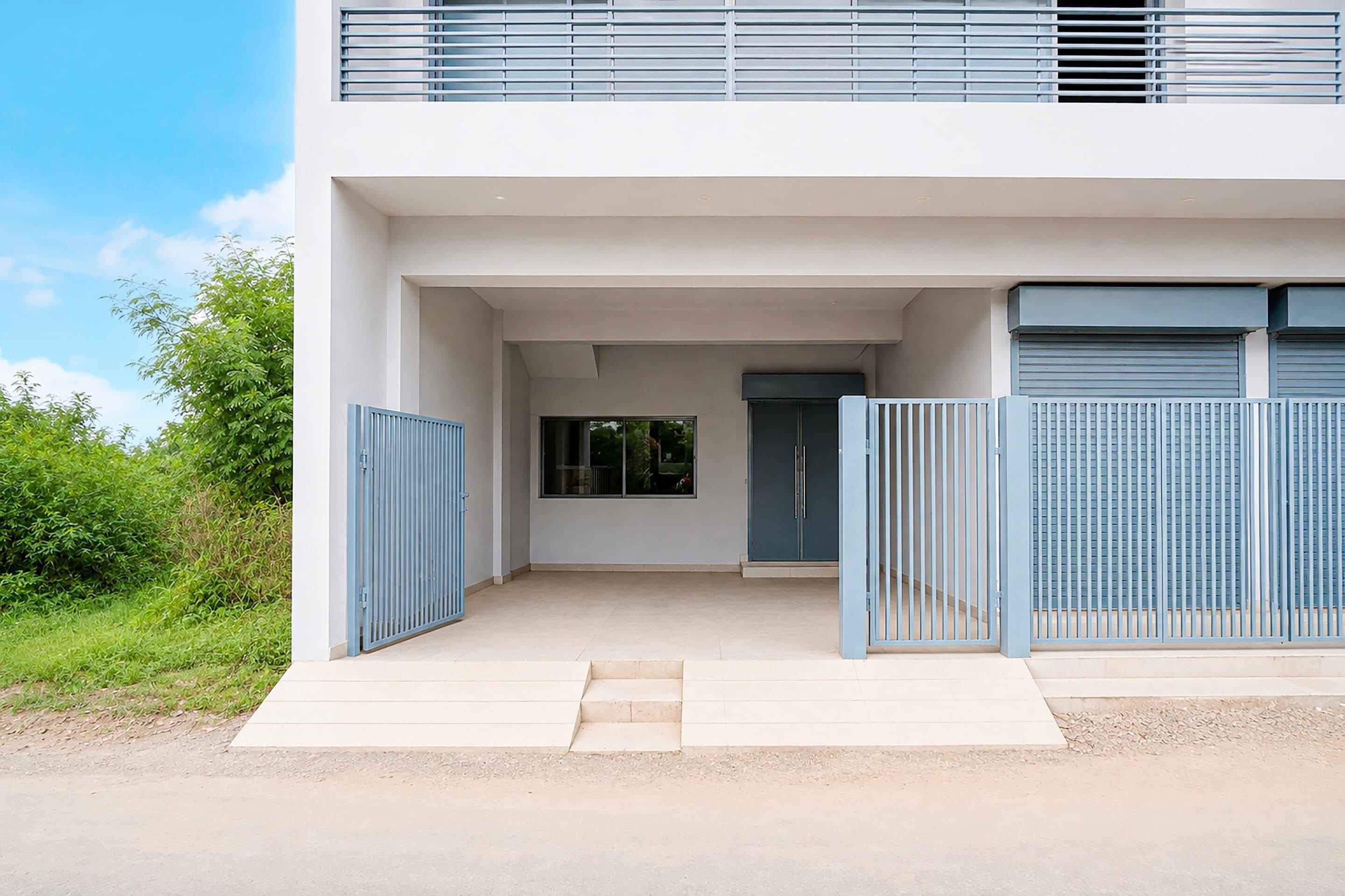 A modern two-story building with a flat roof, a covered entrance with a door, and a window.